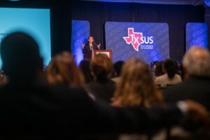 Wide shot of speaker on stage talking to the audience