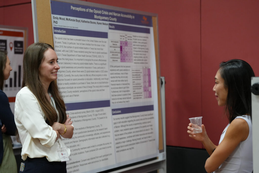 DSC08134 Two women converse at a TxSUS 2026 Poster Session, standing in front of a poster titled "Perceptions of the Opioid Crisis and Narcan Accessibility in Montgomery County" by Emily Wood and colleagues from Sam Houston State University's College of Osteopathic Medicine.